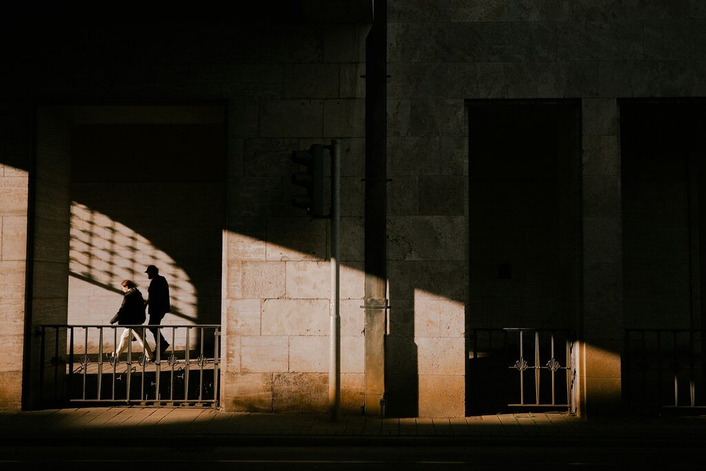 A couple of people walking down a street next to tall buildings