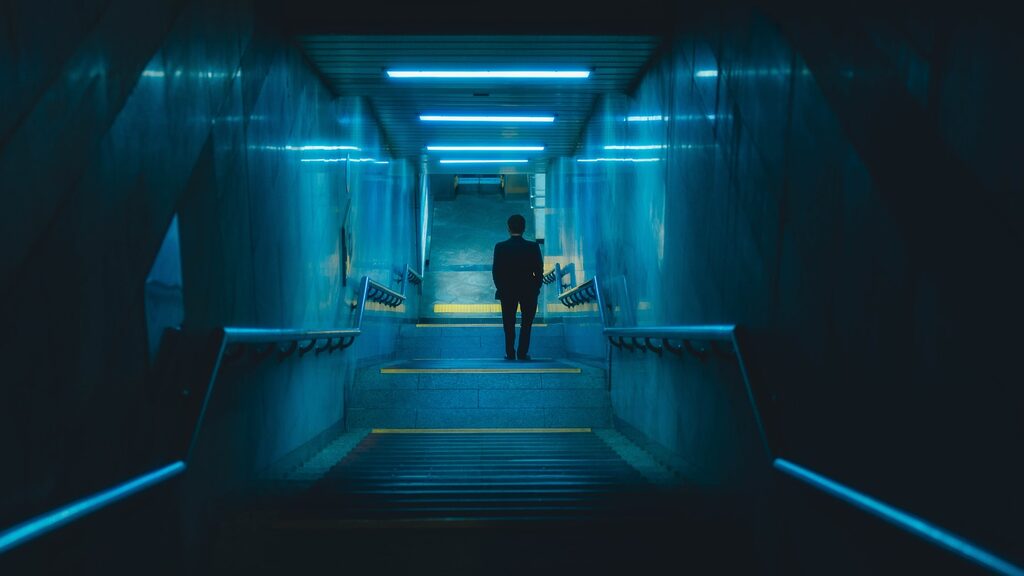 A man is walking down a dark hallway