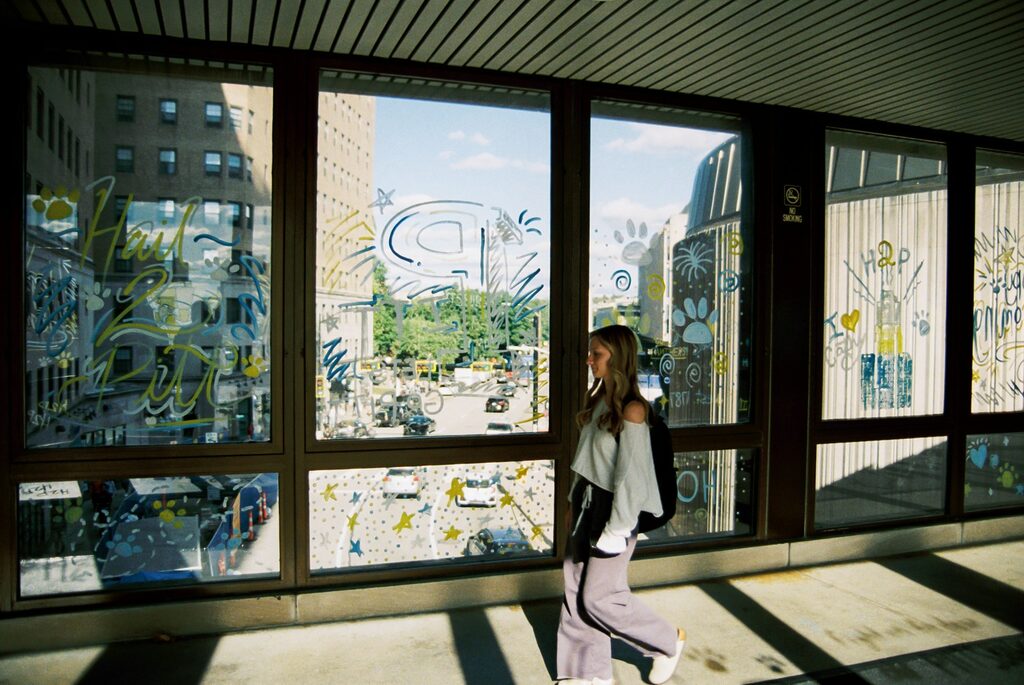 A woman walking down a sidewalk next to a window