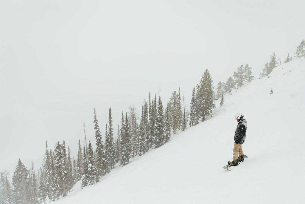 A man riding a snowboard down a snow covered slope